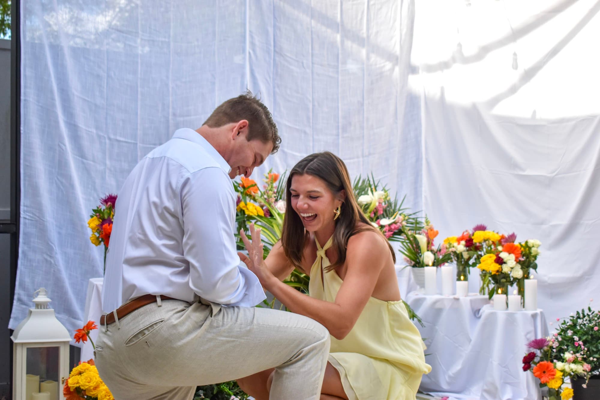 Jon sliding the ring onto Morgan's finger, both of them laughing, flowers and candles behind.