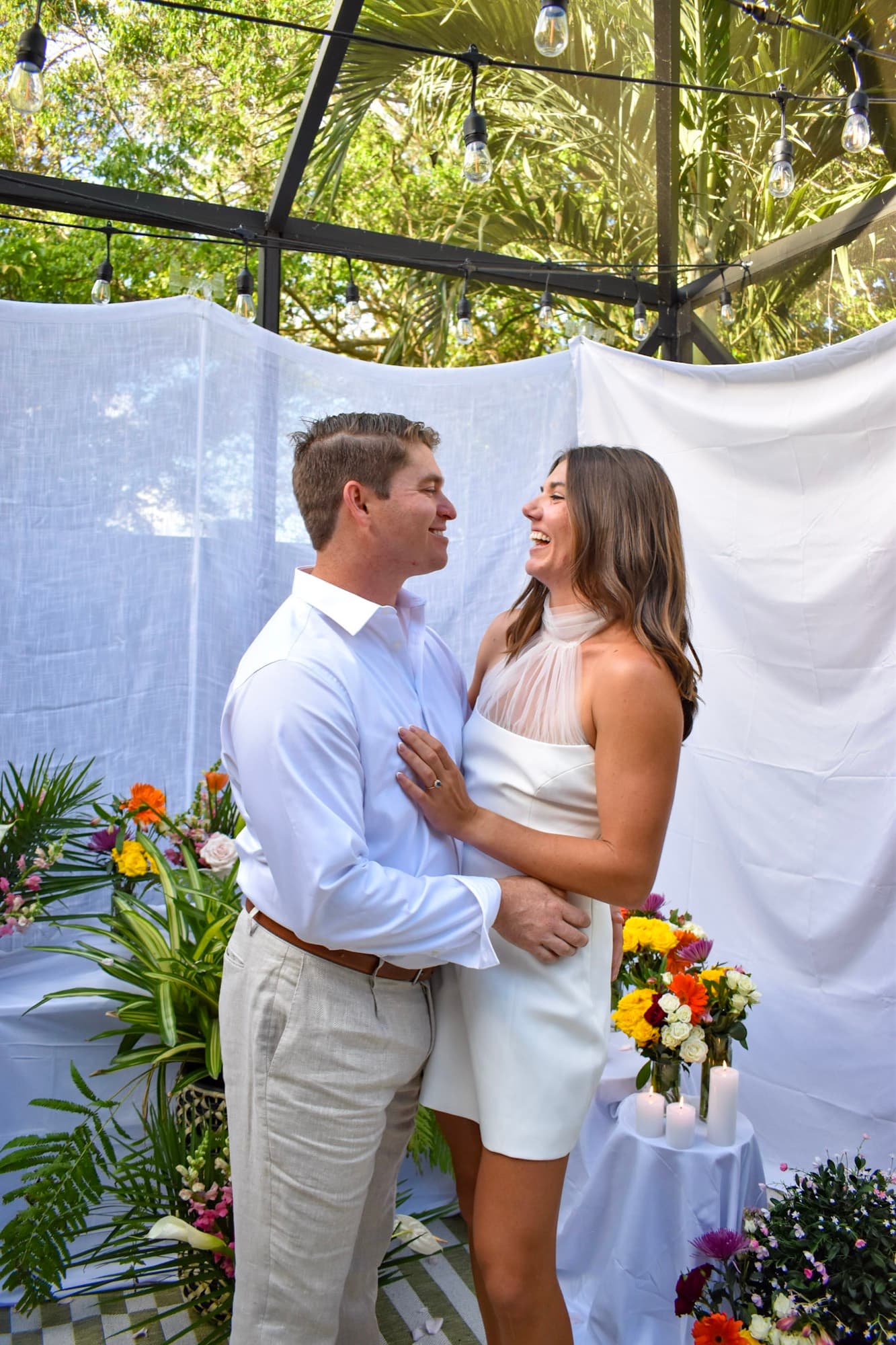 The two of them face to face, mid-laugh, flowers banked around the porch.