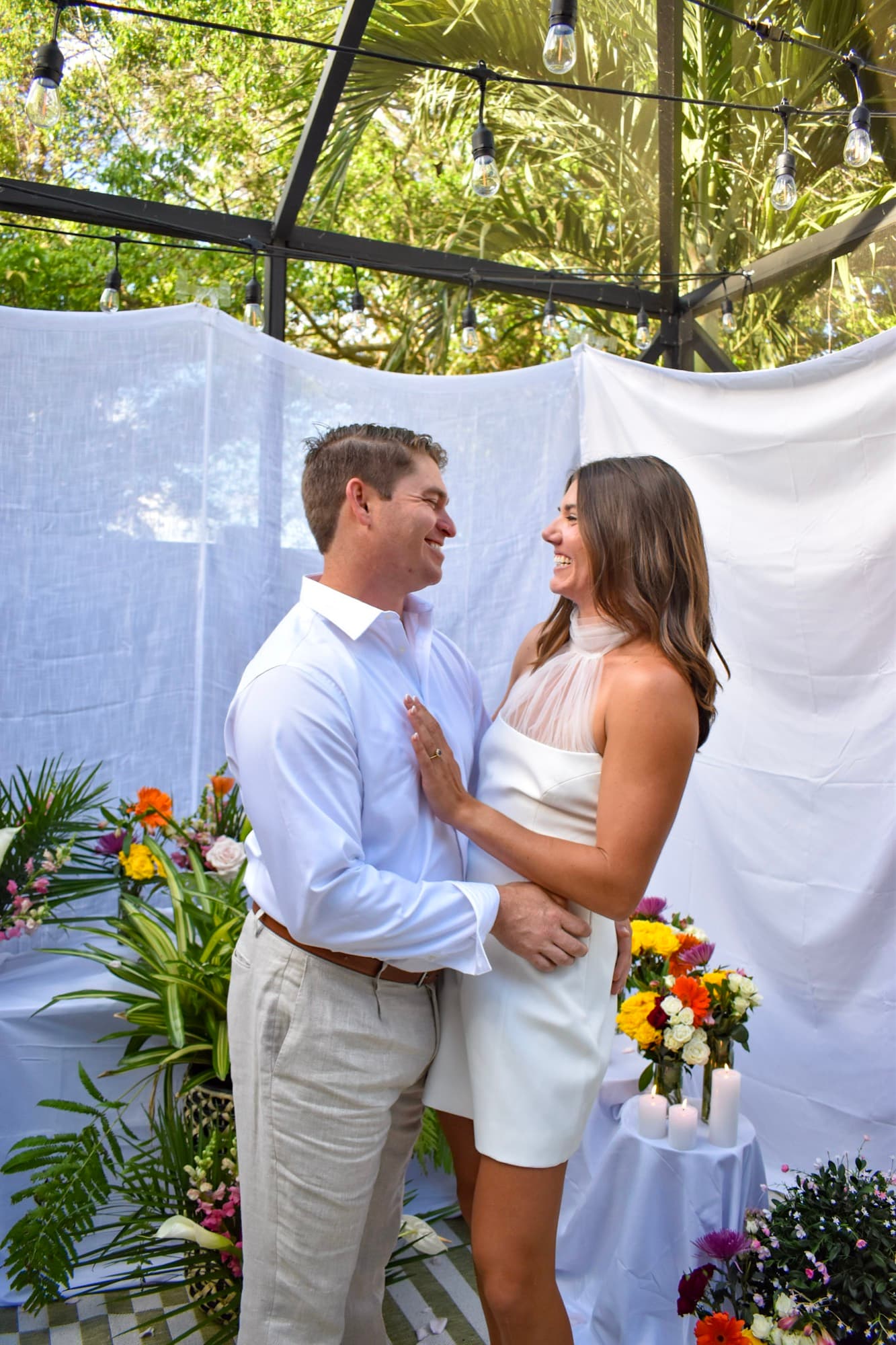 Morgan, now changed into a white dress, holding Jon and laughing, the porch strung with lights behind them.