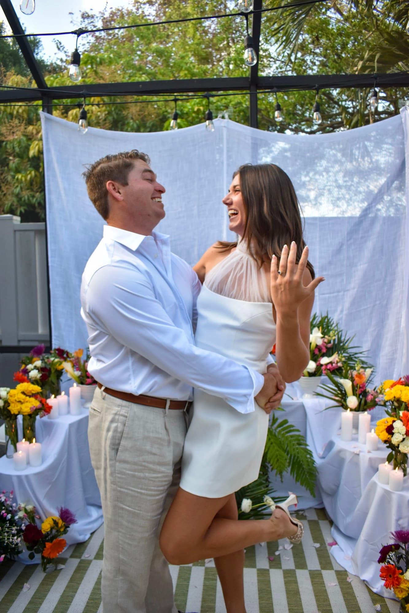 Jon lifting Morgan off her feet as she holds her ring hand up to the camera.