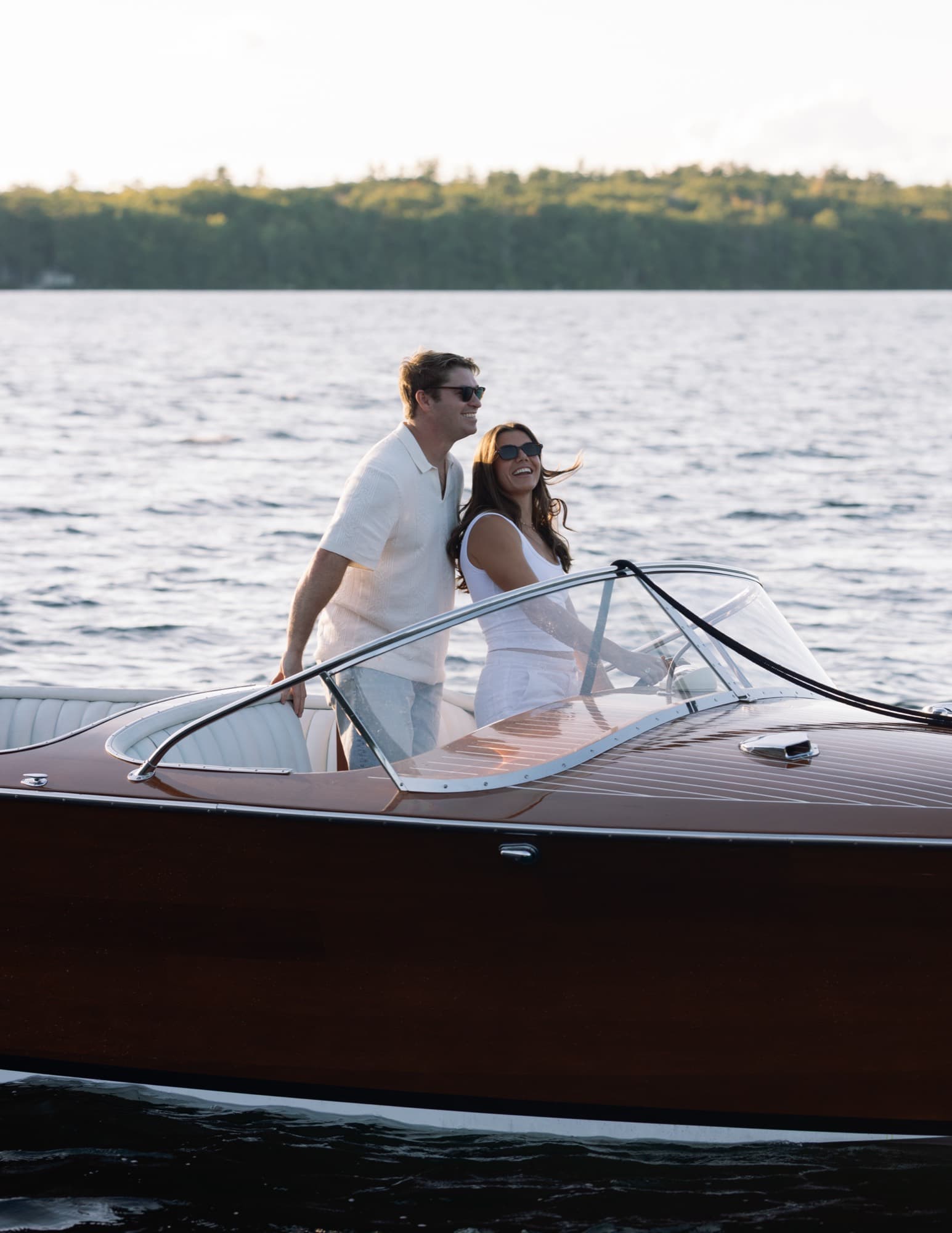 Morgan and Jon standing at the wheel of the runabout as it moves across open water.