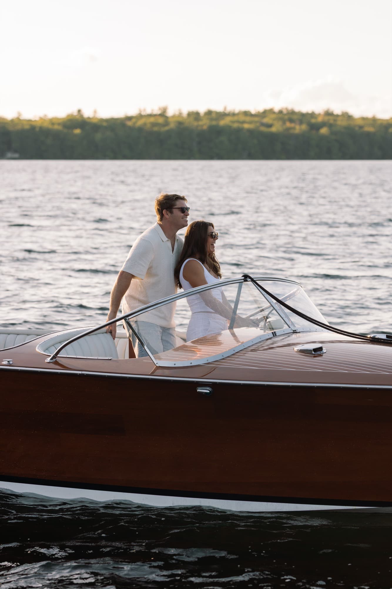 Jon and Morgan standing together behind the windshield of the boat, the lake stretching out beyond.